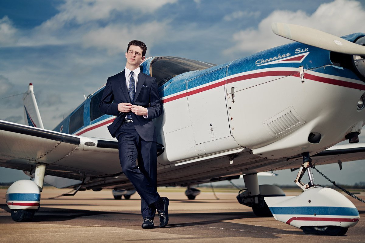 prosper senior photographer with plane of student at the airport in suit